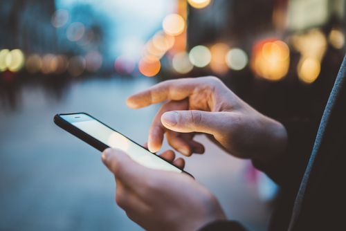 Person using smartphone in a lit street.