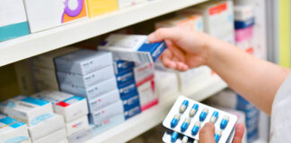 Person selecting medication from pharmacy shelf.